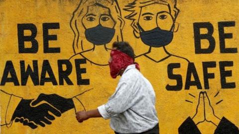 A man walks past a graffiti amid the spread of the coronavirus disease (COVID-19) in Mumbai, India, November 2, 2020.