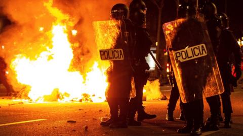 Riot police stand next to a fire in central Barcelona