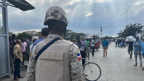 A soldier faces out onto a crowd of Haitians queuing to enter the Dominican Republic via the Dajabon border crossing