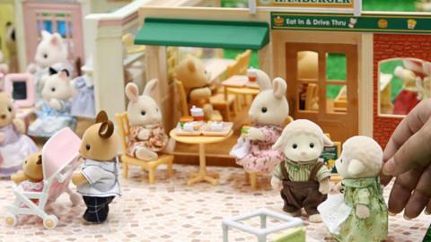 A display of Sylvanian Families toys, with two bunnies sitting at a table eating lunch.