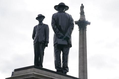 A statue at Trafalgar Square, depicting two men dressed in suits and hats