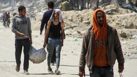 People in Gaza carry a sack containing aid