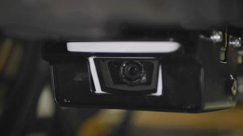 A small camera in black casing fitted to the underside of a train