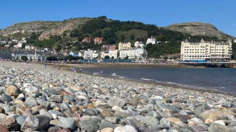 Llandudno's North Shore Beach covered in pebbles with the promenade in the background