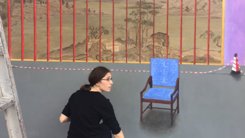 Marine Brossard painting a mural with a blue chair