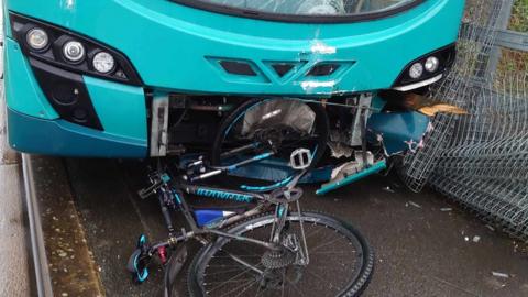A cyclist's bike slightly inside the front of a bus
