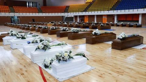 Coffins containing people who died in a migrant shipwreck lie in a sports hall in Crotone, Italy, 28 February 2023