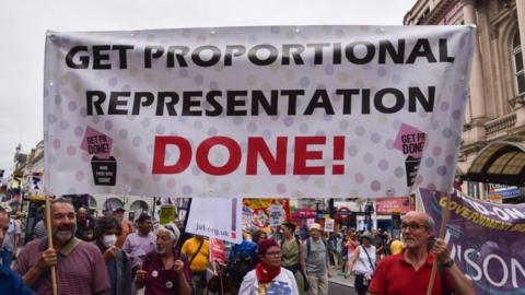 Protesters hold a banner which reads 'Get proportional representation done' during the demonstration in Piccadilly Circus in 2018