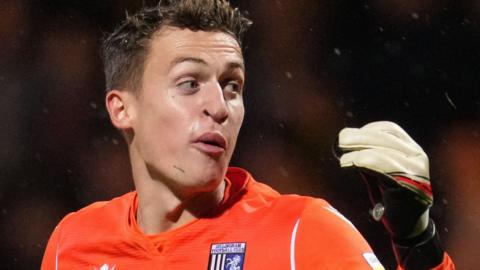 Gillingham goalkeeper Jamie Cumming picked up one of the objects thrown at him at the Abbey Stadium