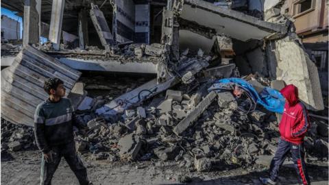 Boys stand in front of the rubble of a building in Rafah in the Gaza Strip