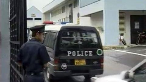 A policeman and police van wait outside a gate at a court house