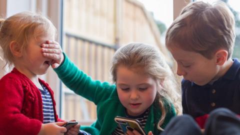 Stock Image of children looking at a mobile phone