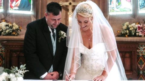 Sophie and John sign their marriage certificate