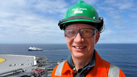 Adura CEO Neil McCulloch on an oil platform with the North Sea in the background
