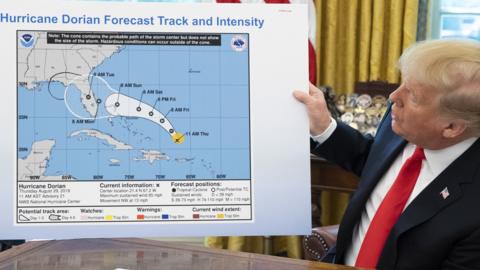 US President Donald Trump holds up a NOAA map of a previously projected path of Hurricane Dorian