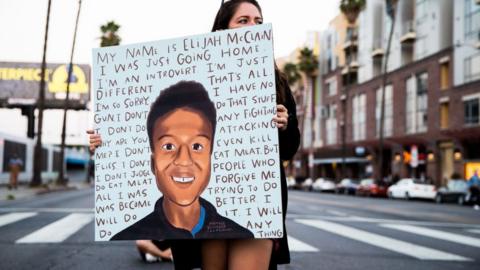 A person holds a sign at a candlelight vigil to demand justice for Elijah McClain on the one year anniversary of his death