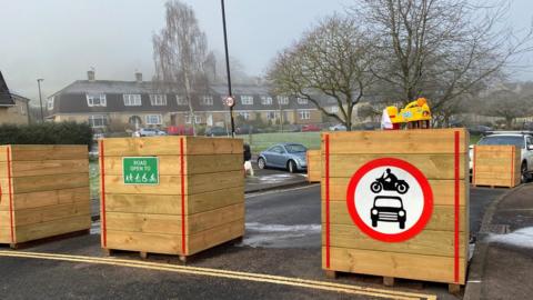 Planters with no traffic sign on a street with houses in the background