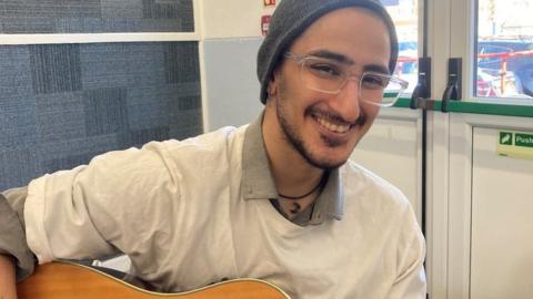 Picture of Faraz smiling with his guitar