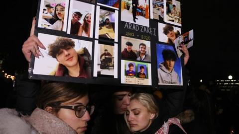 Friends of high school student Arad Zarei held pictures of him at a vigil for victims of the Iran plane crash in Toronto