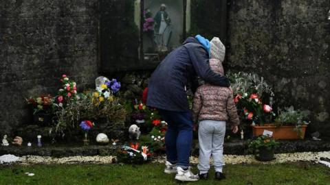 A mother and her daughter pay their respects at the Tuam graveyard where the bodies of 796 babies were uncovered