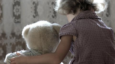 A sad little girl with a teddy bear