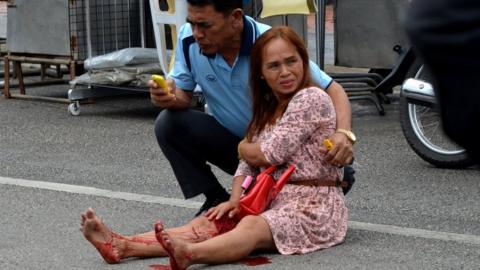 An injured woman sitting in the road after a bomb exploded on 11 August 2016 in Trang.