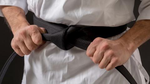 Close-up of a judo competitor's black belt.