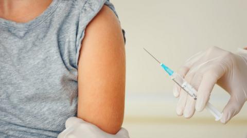 A doctor holds a patient's arm and a needle