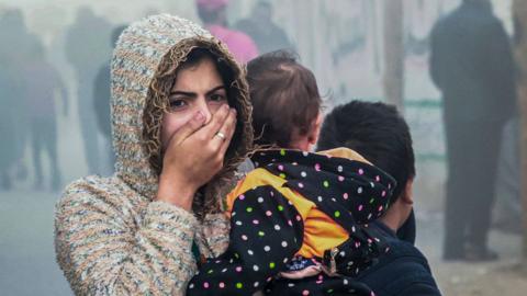 A woman holding a child flees following an Israeli strike in Rafah in the southern Gaza Strip on 23 November