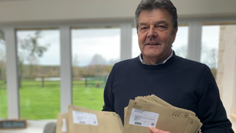 Dylan Davies holding dozens of letter in each of his hands