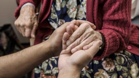 Stock image of an elderly person holding someone's hand