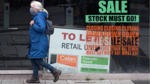 Woman walking past a shop that has shut down