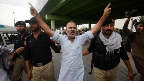 Police personnel arrest a supporter of Pakistan's former prime minister Imran Khan, during a protest in Peshawar