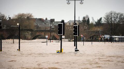 The Whitesands area of Dumfries is deep in flood water with traffic lights halfway covered and a bridge and buildings in the background