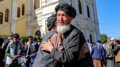 People greet each other after Eid al-Fitr prayers in Kabul, Afghanistan