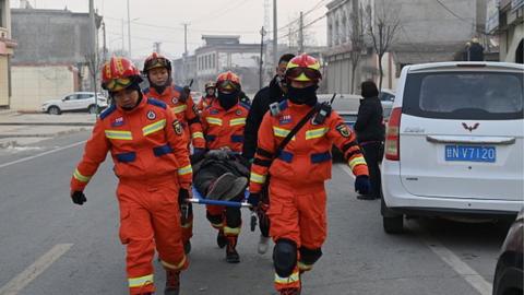 Chinese rescuers carry an injured woman