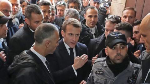 Emmanuel Macron in a crowd, talking to Israeli security