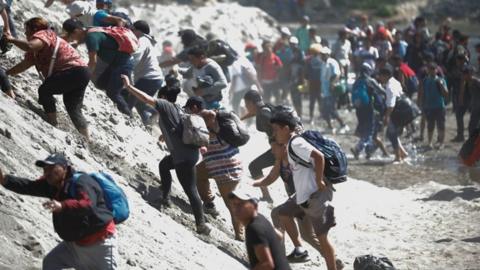 Migrants cross a river between Guatemala and Mexico