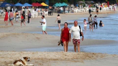 Tourists walking along a beach in Mirissa, Sri Lanka