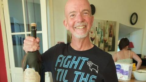 Derby County fan Rich Orme celebrates holding a bottle of champagne