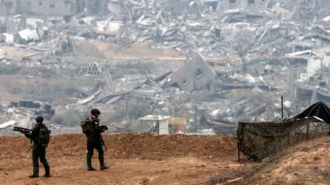 A picture taken in southern Israel near the border with the Gaza Strip on December 12, 2023, shows an Israeli army soldiers on a hill overlooking northern Gaza