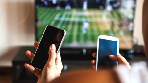 People gambling in front of a tennis match on TV.