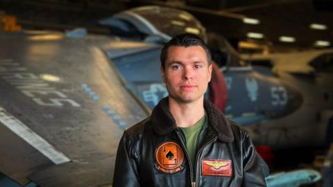 Captain Earl Ehrhart stands in front of a Harrier jet fighter