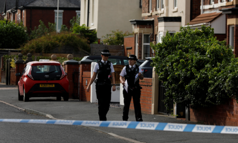 Two uniformed female police officers walk along Hart Street, close to where the Southport attack happened. A streamer of blue and white police tape is in the foreground of the shot. 