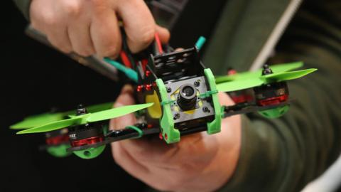 A drone racing enthusiast prepares a small multirotor racing drone in the Dronemasters hall at the 2016 CeBIT digital technology trade fair