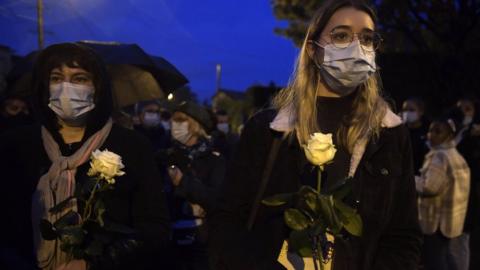 Two women march holding flowers