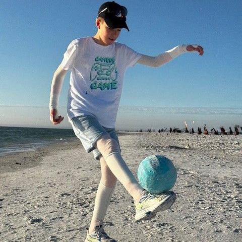 Gabrielius Misurenkovas playing football on a beach with bandages around his legs