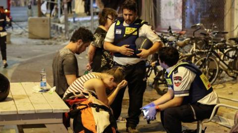 Israeli civilians helped by emergency services after a Hamas rocket attack