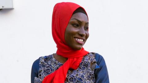 Dienaba Balde wears a blue outfit plus red accessories