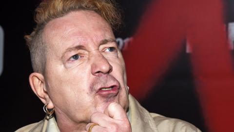 John Lydon - aka Johnny Rotten - posing with a hand on his chin, as though thinking